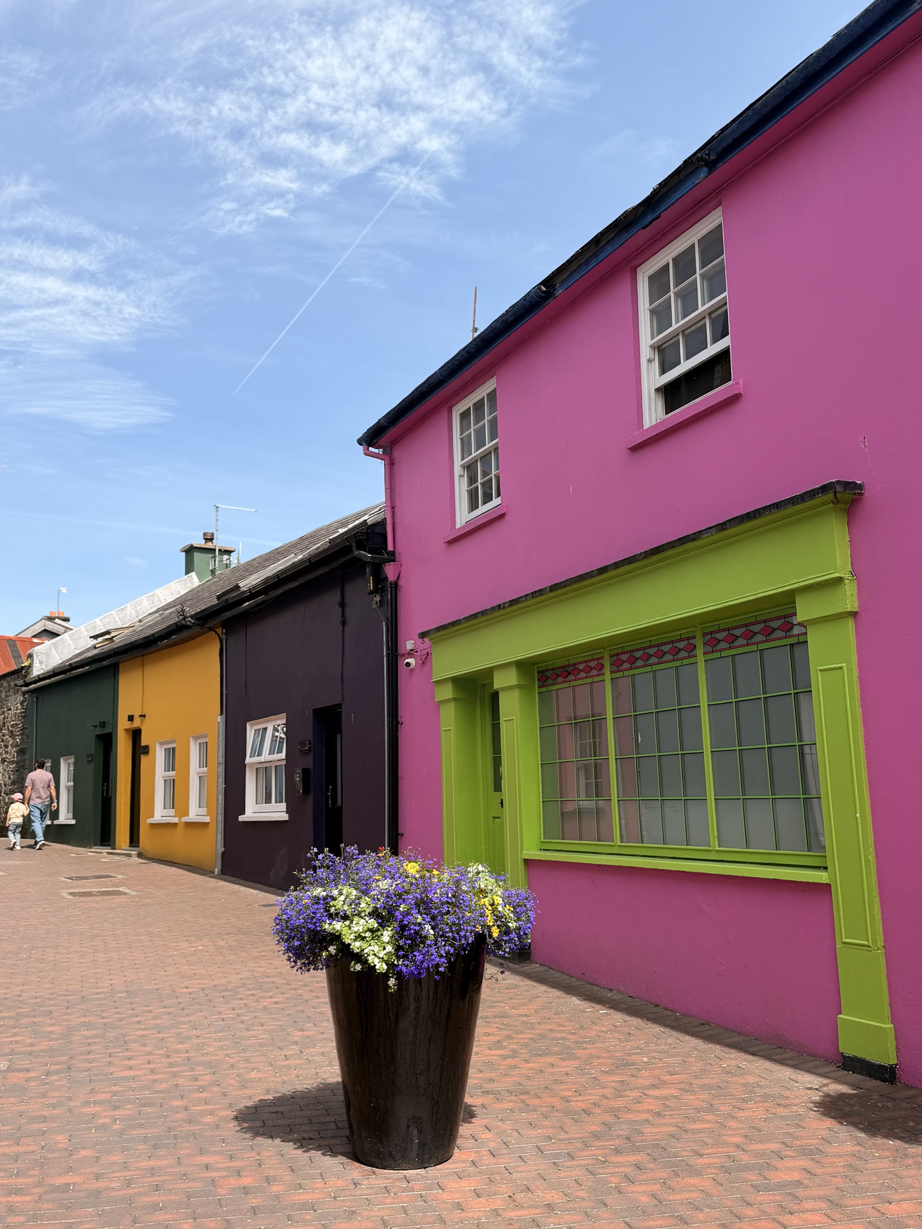 Painted pink and green shopfronts beneath a blue sky in Kinsale, Cork