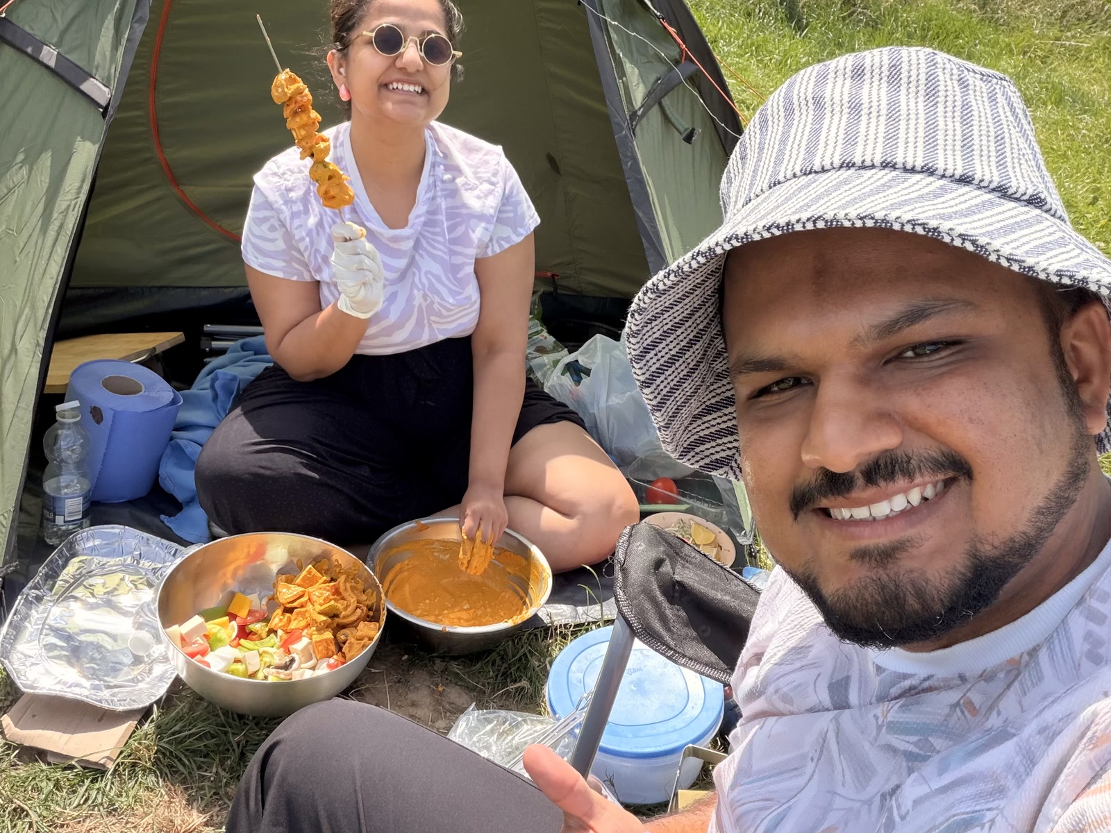 An Indian couple preparing a barbecue beside their tent in West Cork