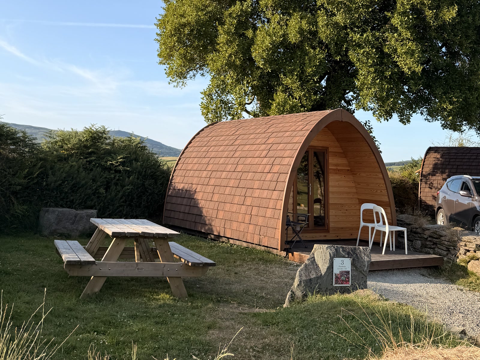 A wooden camping pod and picnic table at Top of the Rock in West Cork